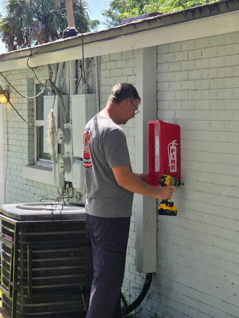 Technician installing outdoor fire extinguisher cabinet