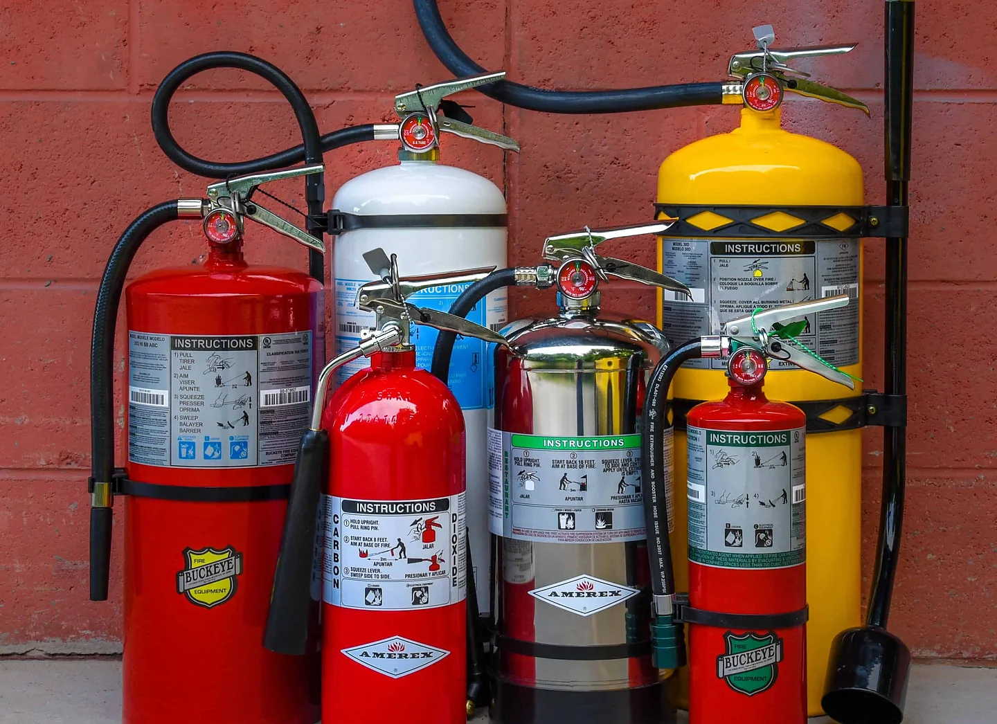 Group of fire extinguishers against red wall
