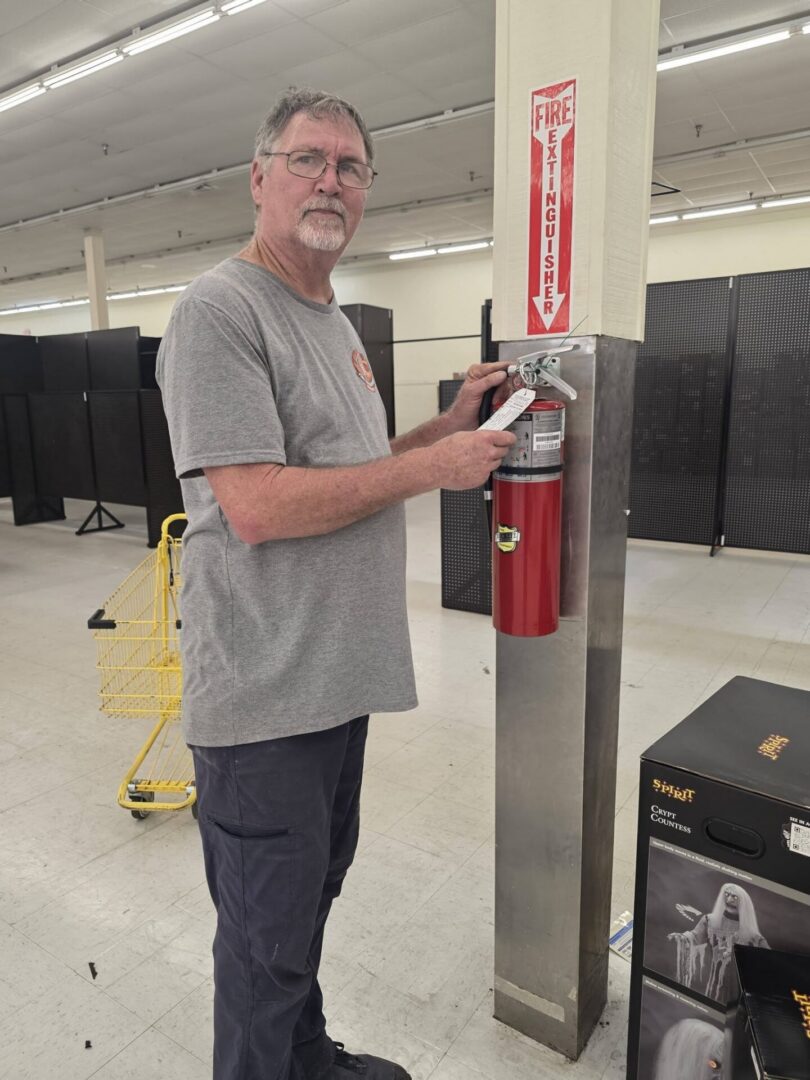 Man checking wall-mounted fire extinguisher